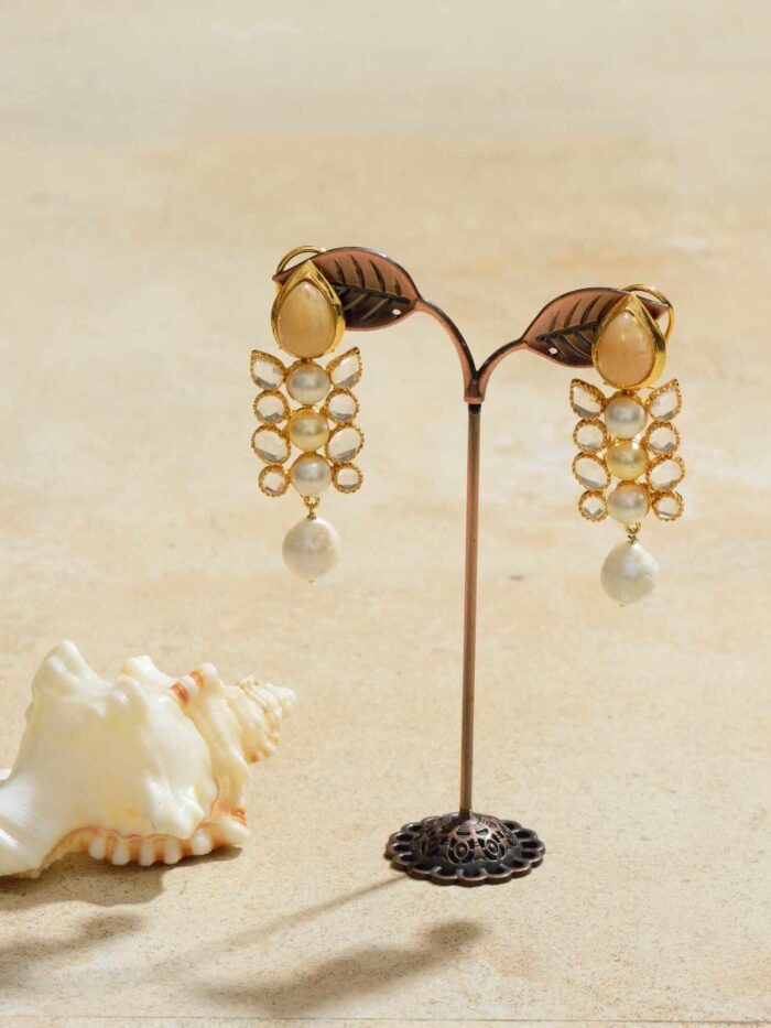 Gold earrings featuring lustrous pearls that dangle elegantly, reflecting light with a subtle twinkle.