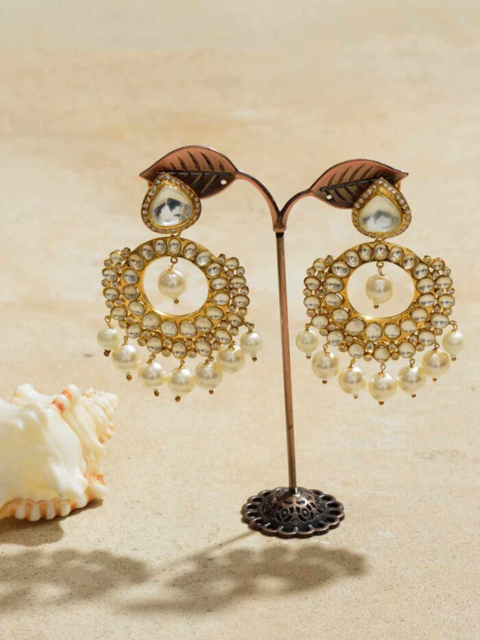 Gold dangler earrings with prominent regal pearls.